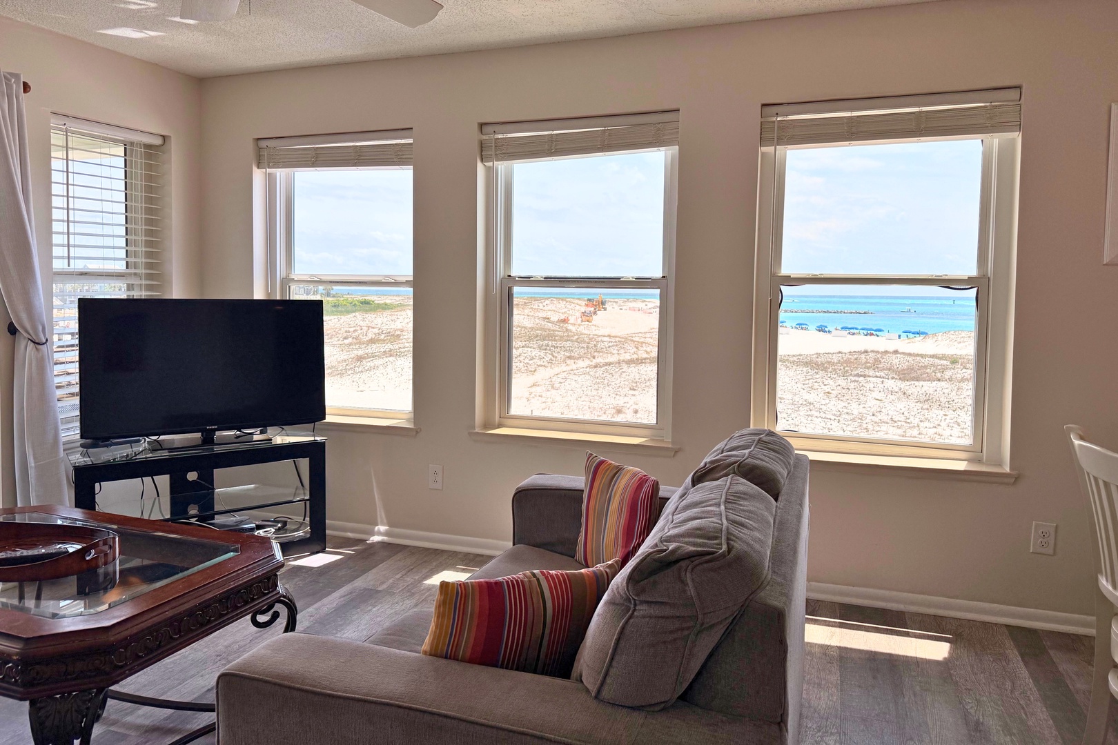 Wake up to panoramic ocean views through expansive windows framing turquoise waters and sandy shores. Relax in your comfortable living space while watching waves roll in just steps away.