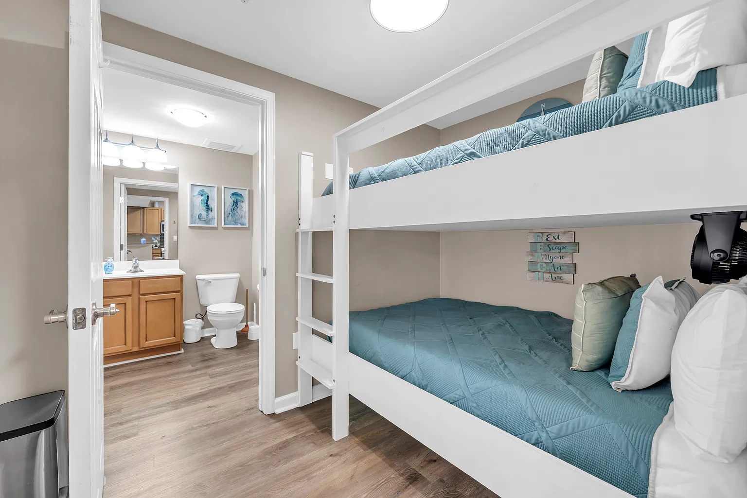 Your cozy bunk room features comfortable twin beds with soft teal bedding and a convenient en-suite bathroom for easy nighttime trips.