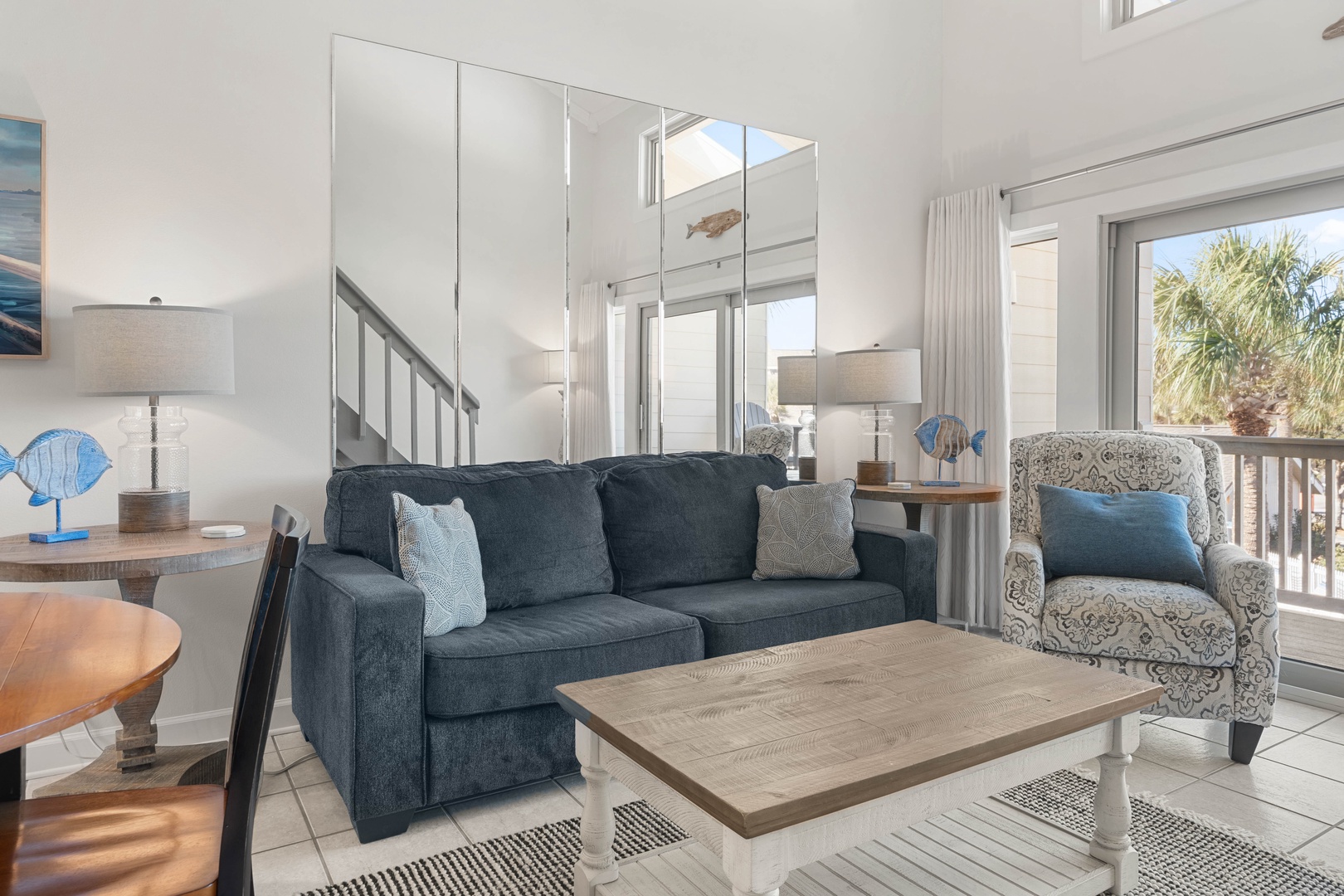 Sink into coastal comfort in your bright living space with stylish furnishings and gentle natural light streaming through large windows.