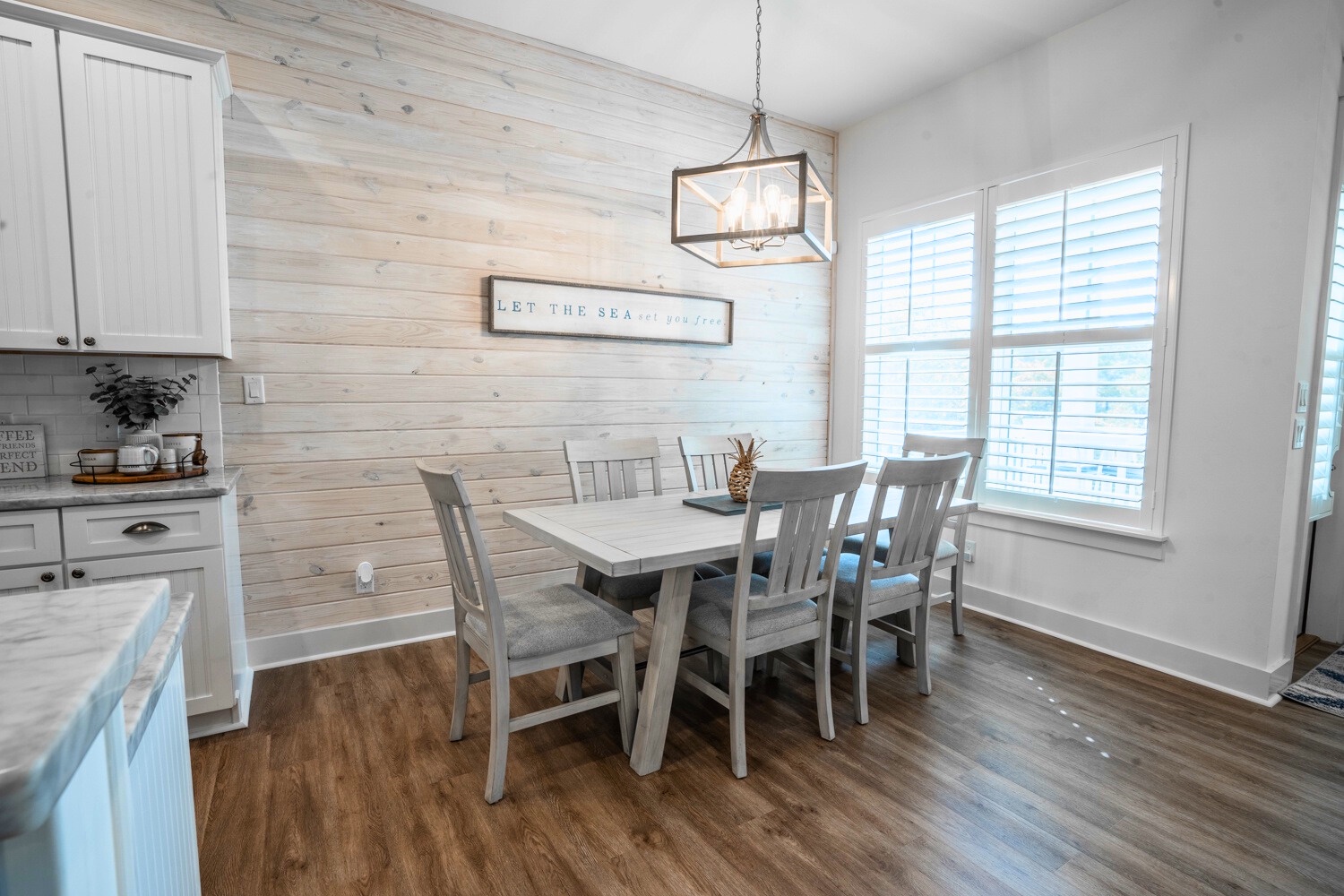 Light-filled coastal dining space with shiplap walls, farmhouse table, soft neutrals, and relaxed beachside charm.