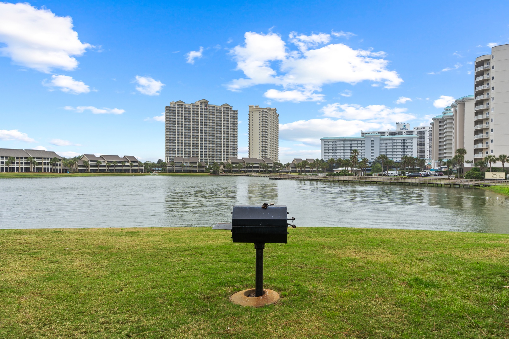 Lakefront park area with barbecue facilities surrounded by high-rise buildings and waterfront views.