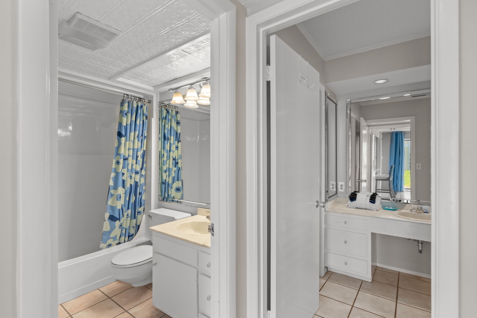 Bright and spacious bathroom with a tub/shower combo and cheerful blue-accented decor, plus a separate vanity area for your morning routine.