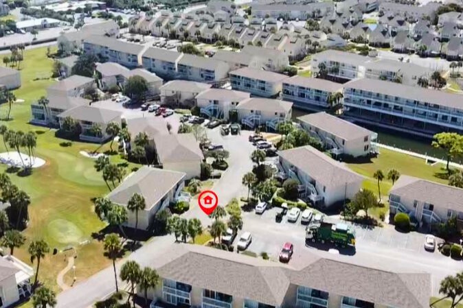Aerial view of the vacation rental property nestled within a well-maintained residential community with landscaped grounds and convenient parking.