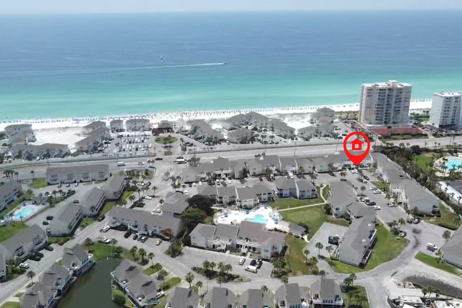 Aerial view of beachfront resort community with pristine white sand beach and emerald waters just steps away from the property.