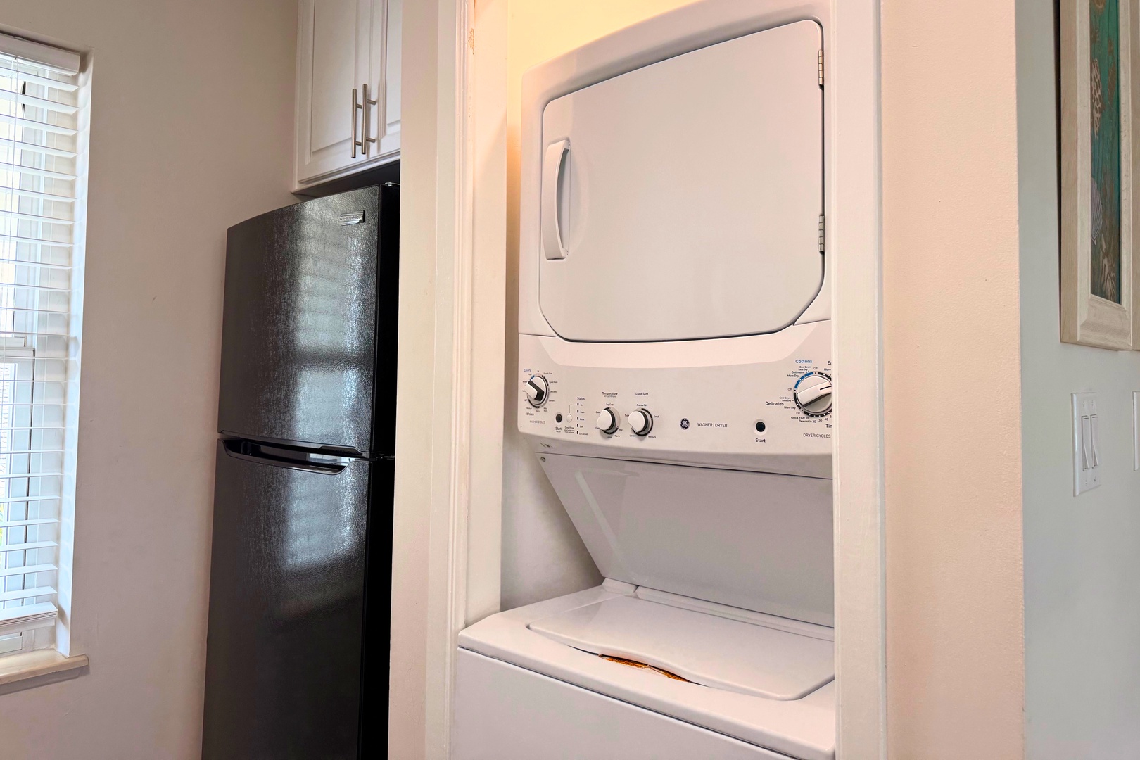 A stacked washer-dryer unit nestles conveniently in the kitchen alcove, with a sleek refrigerator nearby—so you can keep essentials close and your wardrobe fresh throughout your stay.