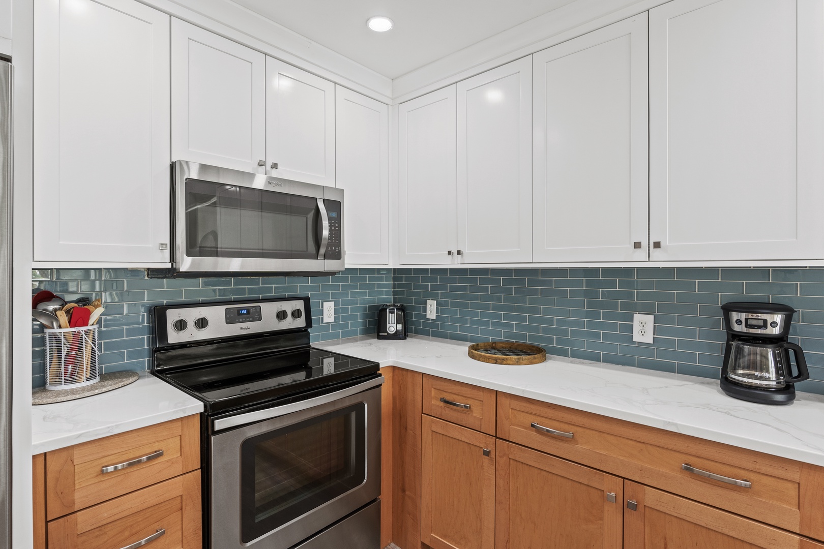 Step into your fully equipped kitchen featuring sleek two-tone cabinetry, modern stainless appliances, and elegant subway tile backsplash.