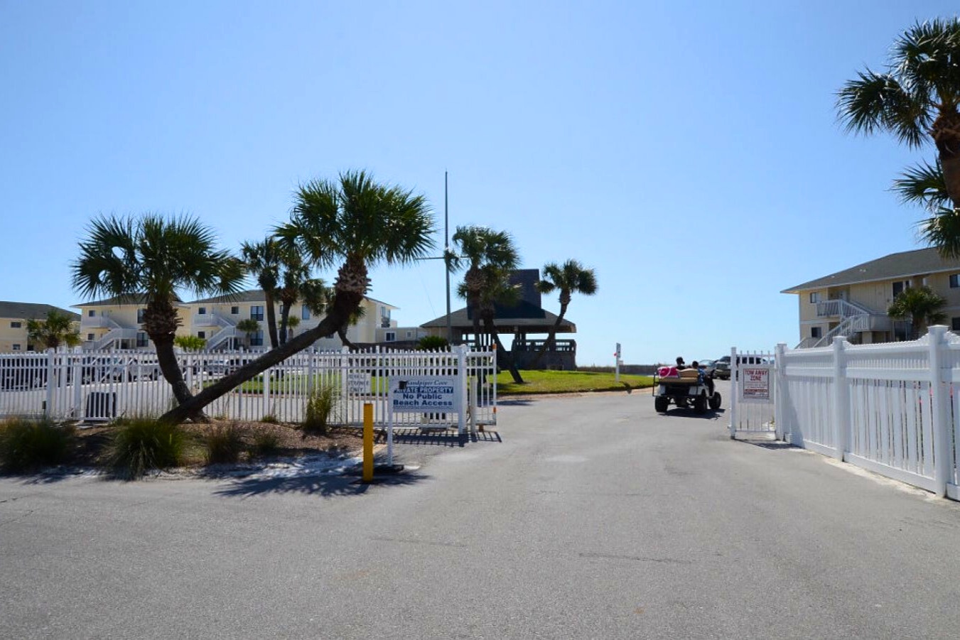 Private beach access entrance with palm-lined surroundings, gated entry, and easy walk or golf cart access to sugar-white sand and emerald Gulf waters just steps away.