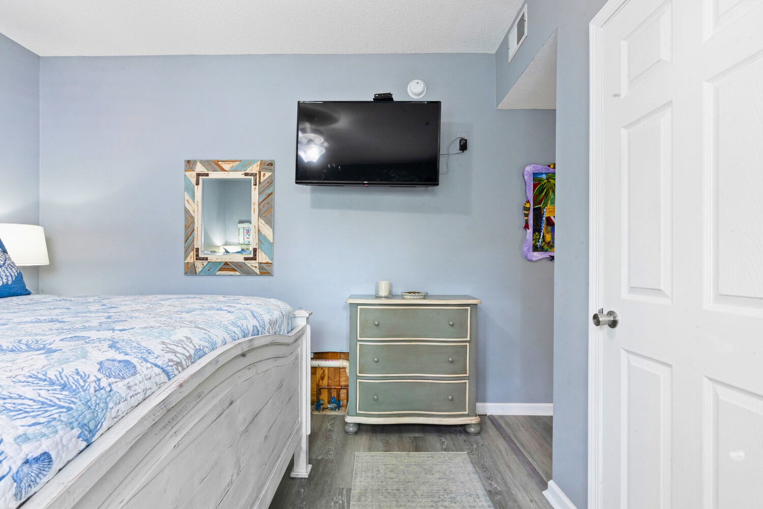 Relax in your serene coastal-themed bedroom with soothing blue walls, comfortable bedding, and your own wall-mounted TV for evening entertainment.