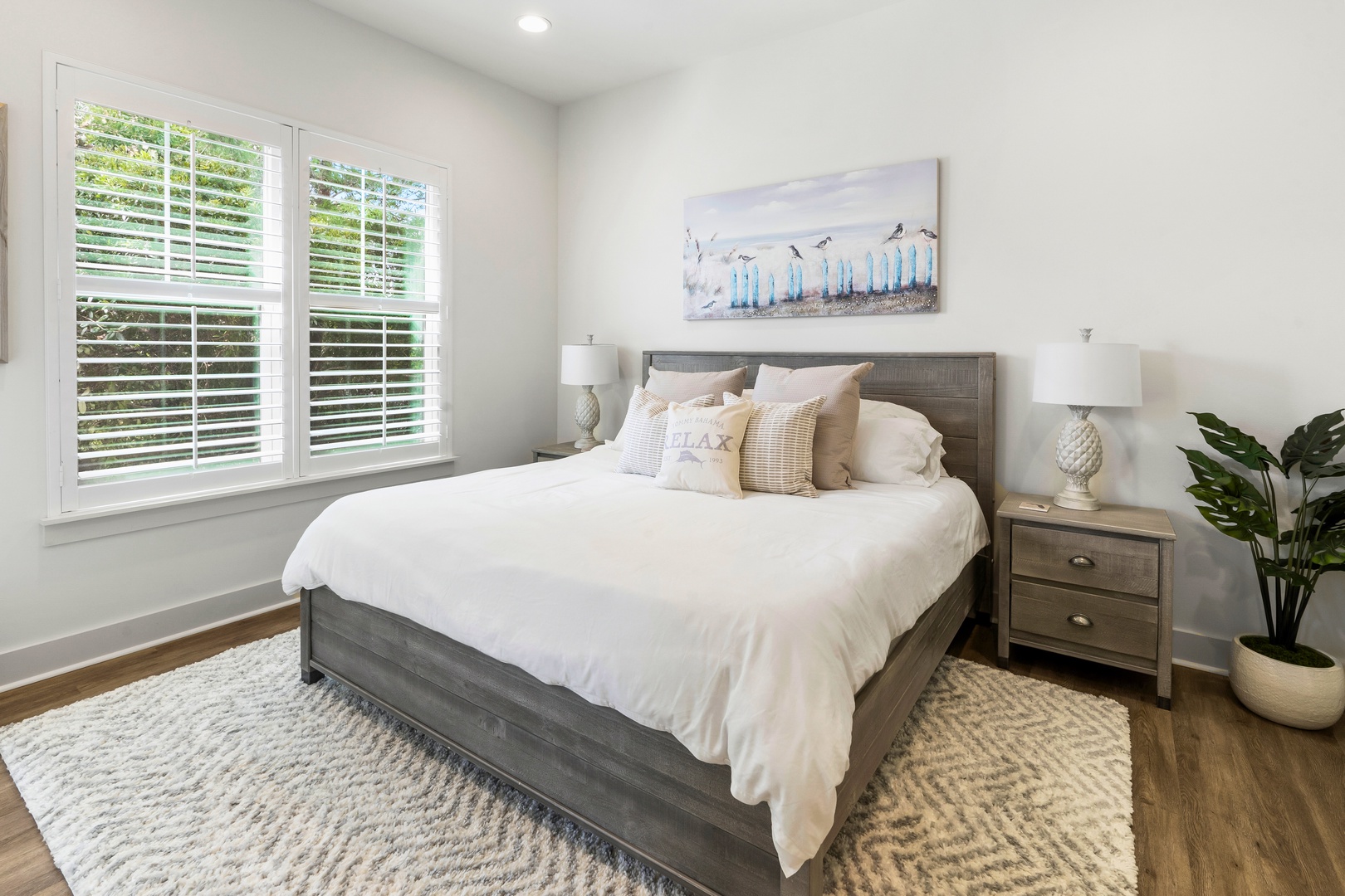 Your peaceful retreat awaits with crisp white linens, natural light flooding through plantation shutters, and coastal artwork setting the mood.