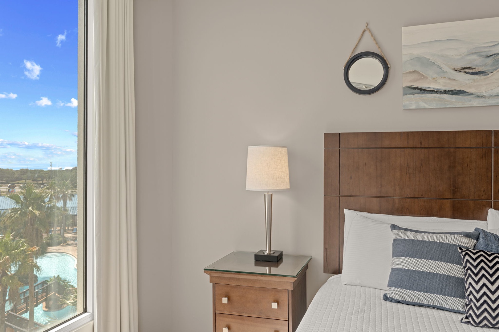 Your private sanctuary awaits with serene coastal artwork, plush bedding, and stunning views of the resort's waterpark and palms just outside your window.