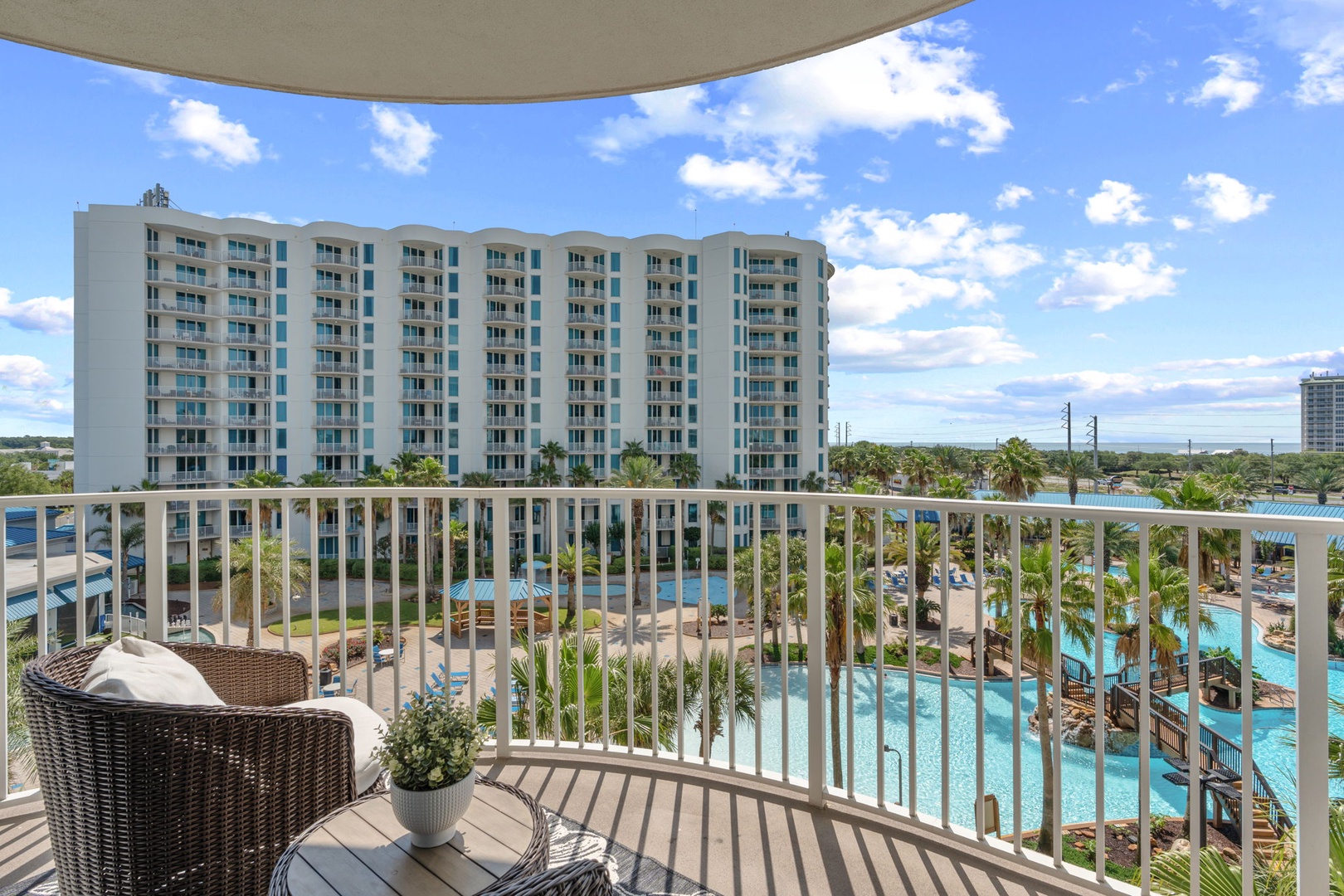 A pristine pool view stretches beneath sunny skies, framed by swaying palms and a spacious balcony retreat—your peaceful oasis awaits.
