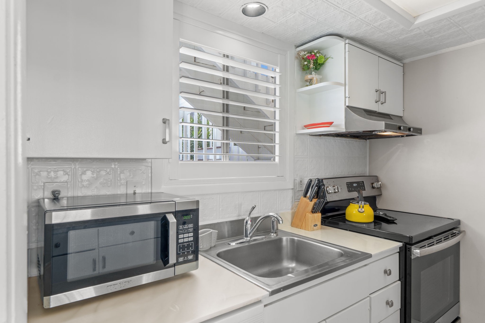 The kitchen features everything needed for easy meal prep, including a stovetop, microwave, coffee maker, and convenient counter space. Bright coastal touches and an open layout make the space feel comfortable and inviting.