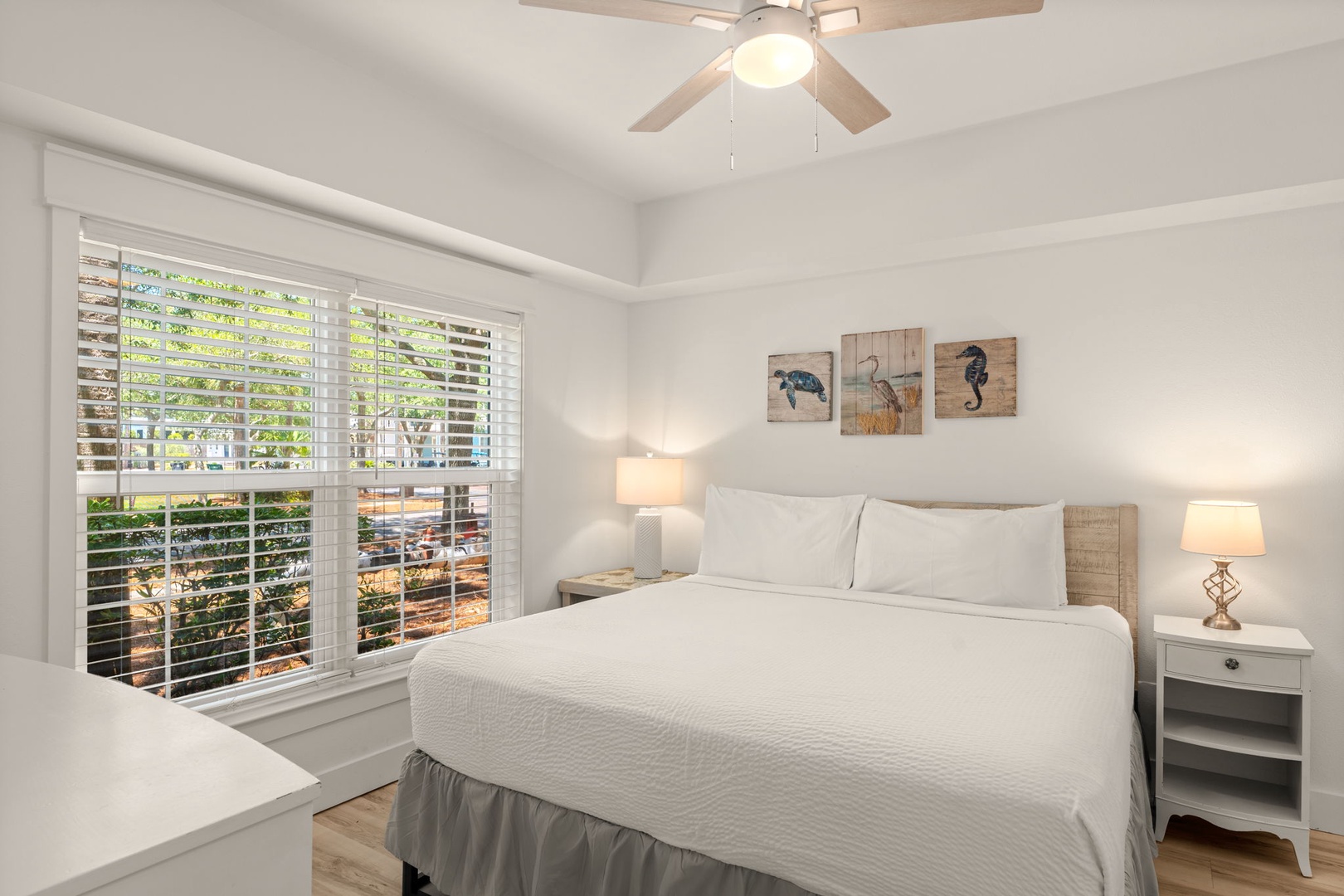 Drift off to sleep in this peaceful bedroom with crisp white linens, coastal decor, and gentle natural light—your perfect retreat after a day exploring.