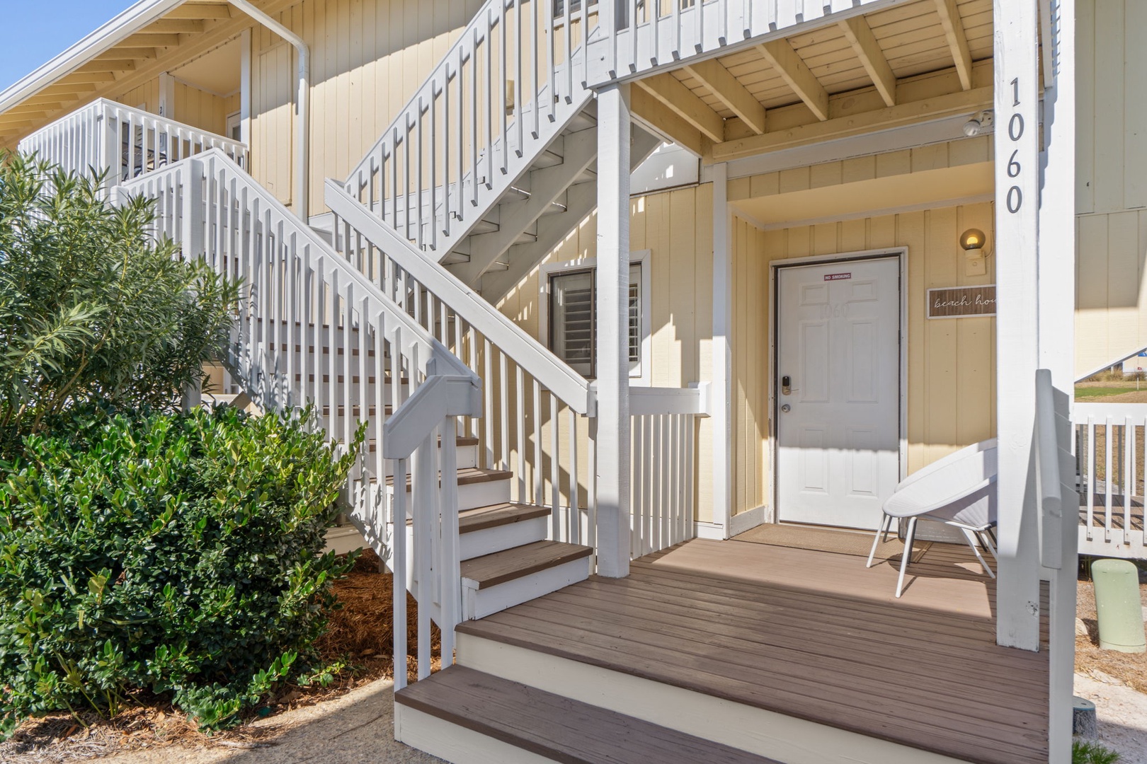 A welcoming coastal-style entrance awaits at unit 1060, featuring a shaded front deck with seating.