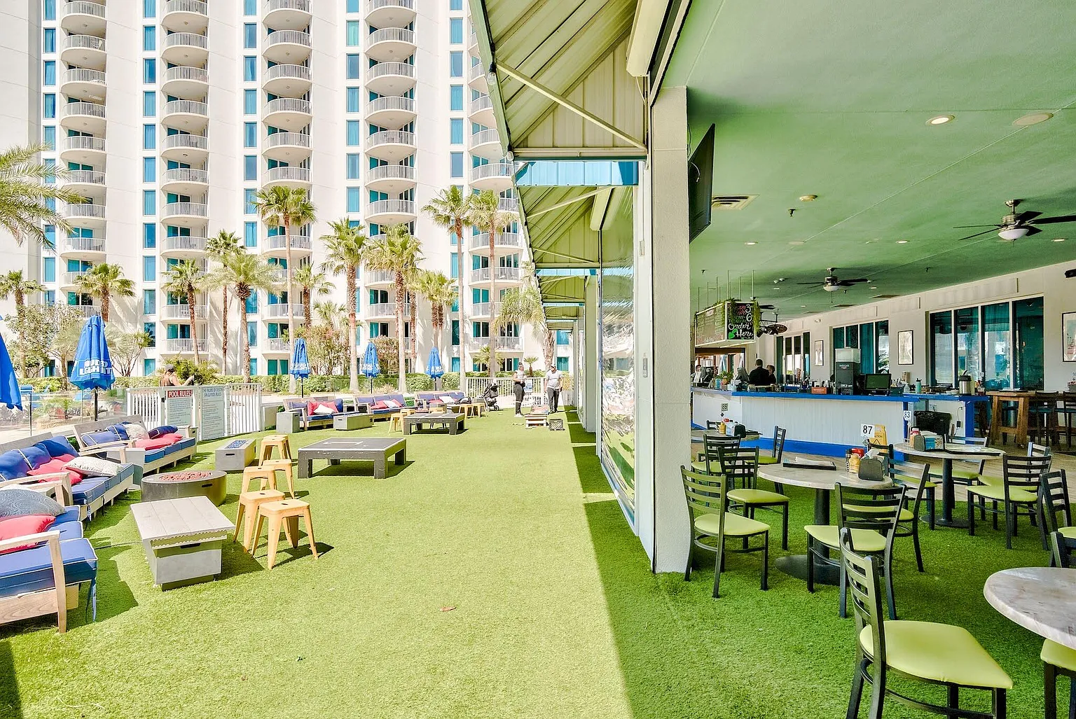 Relax on the vibrant outdoor terrace with fresh green turf under your feet, comfy lounge seating, and dining tables perfect for meals al fresco.