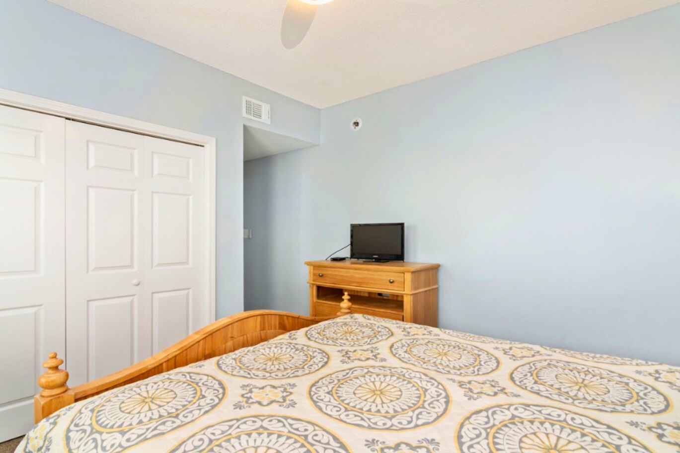 Rest easy in your comfortable bedroom with soft blue walls and warm wood accents creating a peaceful retreat.