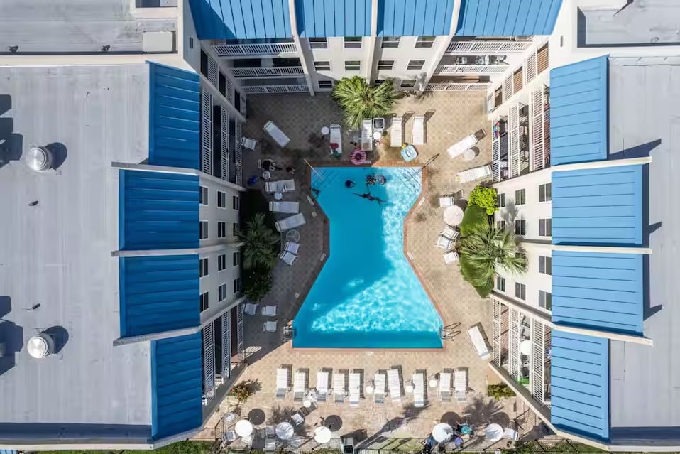 Resort-style pool oasis with loungers, palms & sunshine—perfect for relaxing just steps from your door.