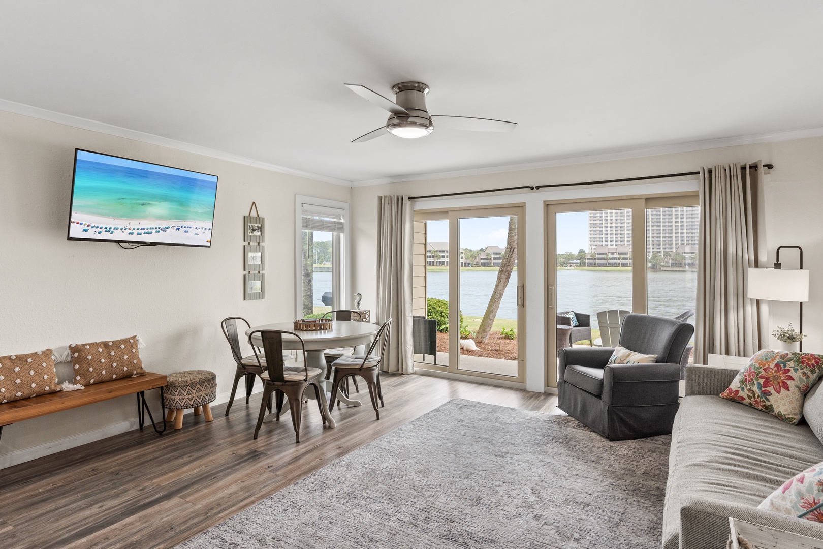 Relax in your spacious waterfront living room with stunning lake views through floor-to-ceiling windows. Comfortable seating and dining area await your arrival.