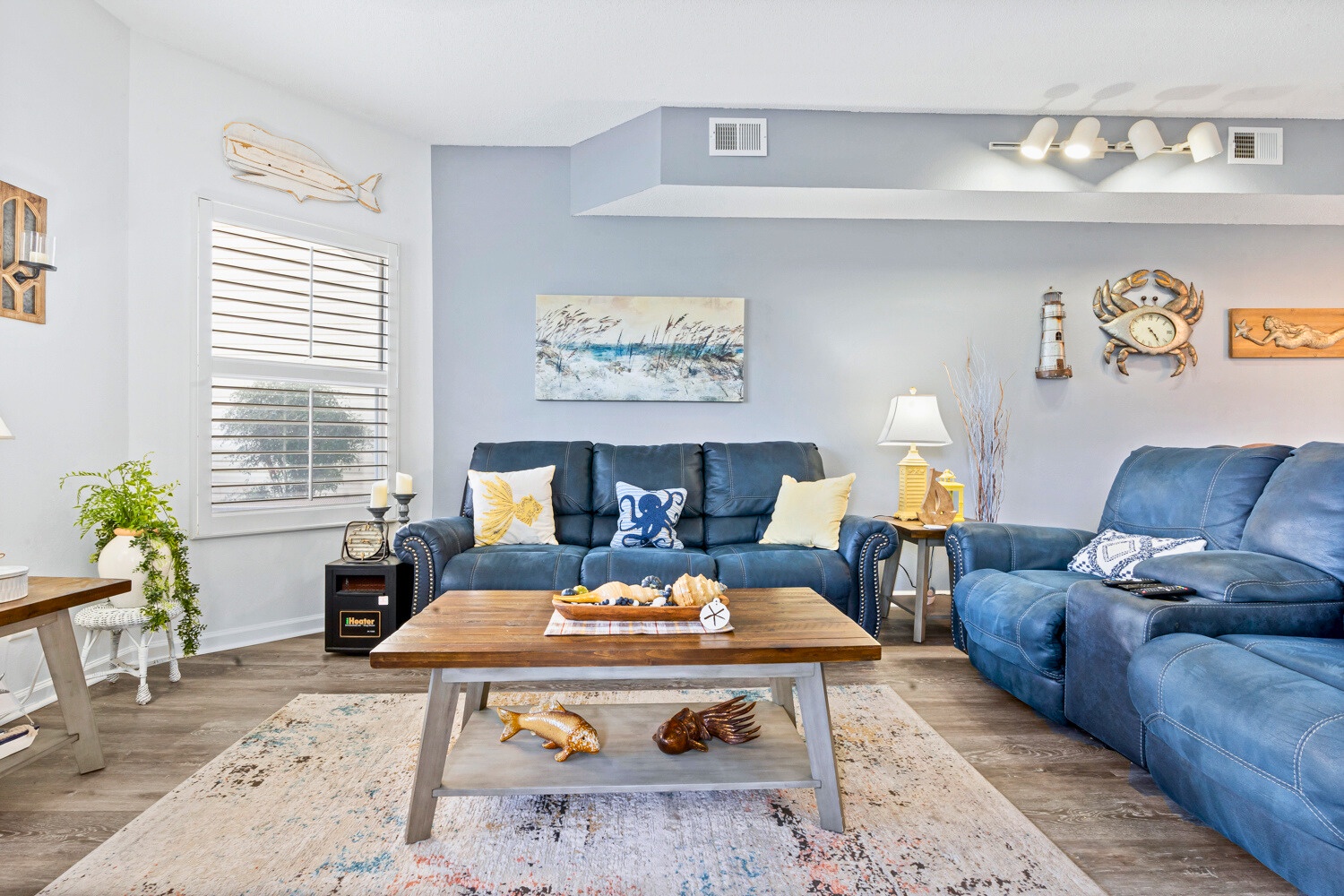 Sink into plush blue sofas in your coastal-themed living room, where nautical artwork and warm lighting create the perfect retreat for relaxing evenings.