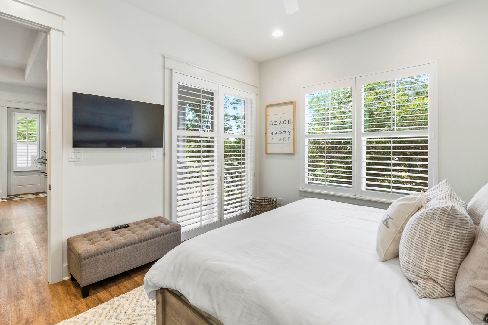 Drift off in your serene bedroom sanctuary with crisp linens, peaceful garden views through plantation shutters, and modern entertainment at your fingertips.