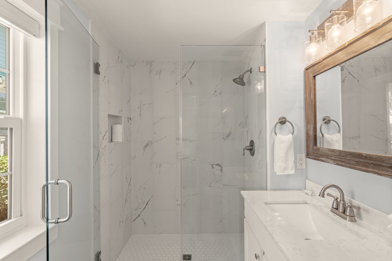 Step into your private marble-tiled retreat, where bright white surfaces and warm wood accents create a spa-like sanctuary. The spacious walk-in shower awaits your morning refresh.