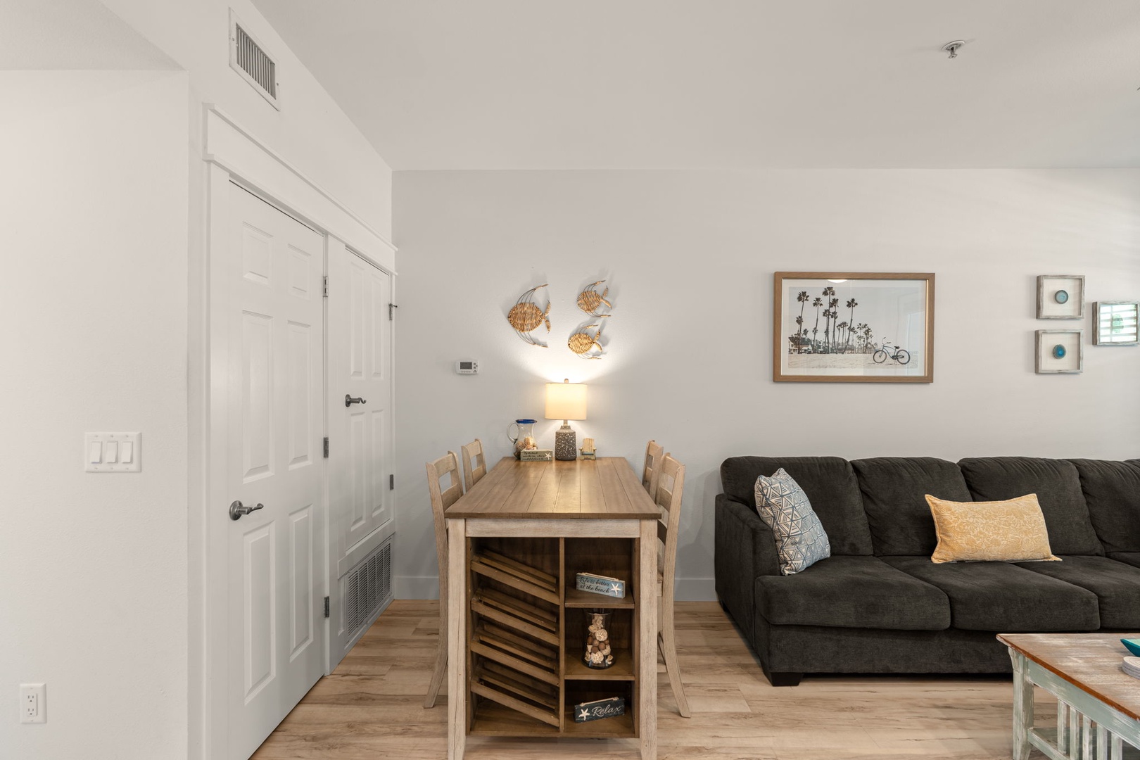 Picture yourself relaxing in this bright, coastal-inspired living space with comfy seating, a welcoming dining table, and charming beach-themed artwork. Your perfect home base for vacation adventures awaits.