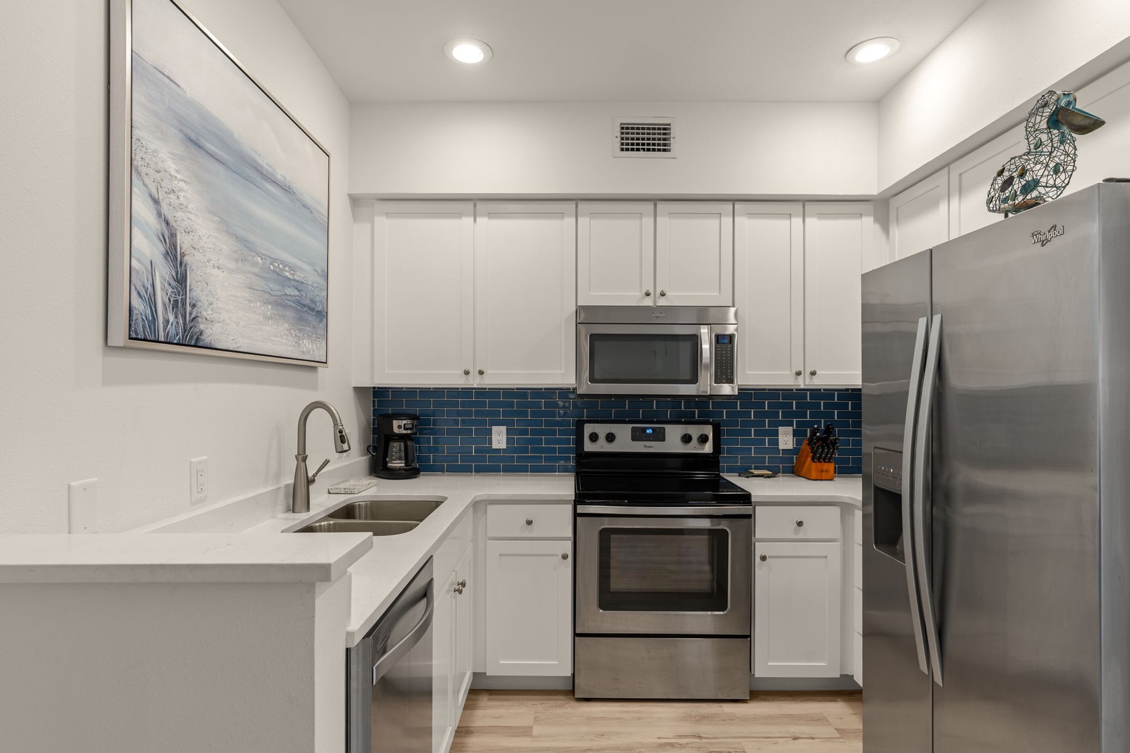 Step into your fully equipped kitchen featuring sleek stainless steel appliances, modern white cabinetry, and stylish blue subway tile backsplash—perfect for preparing your favorite meals during your stay.