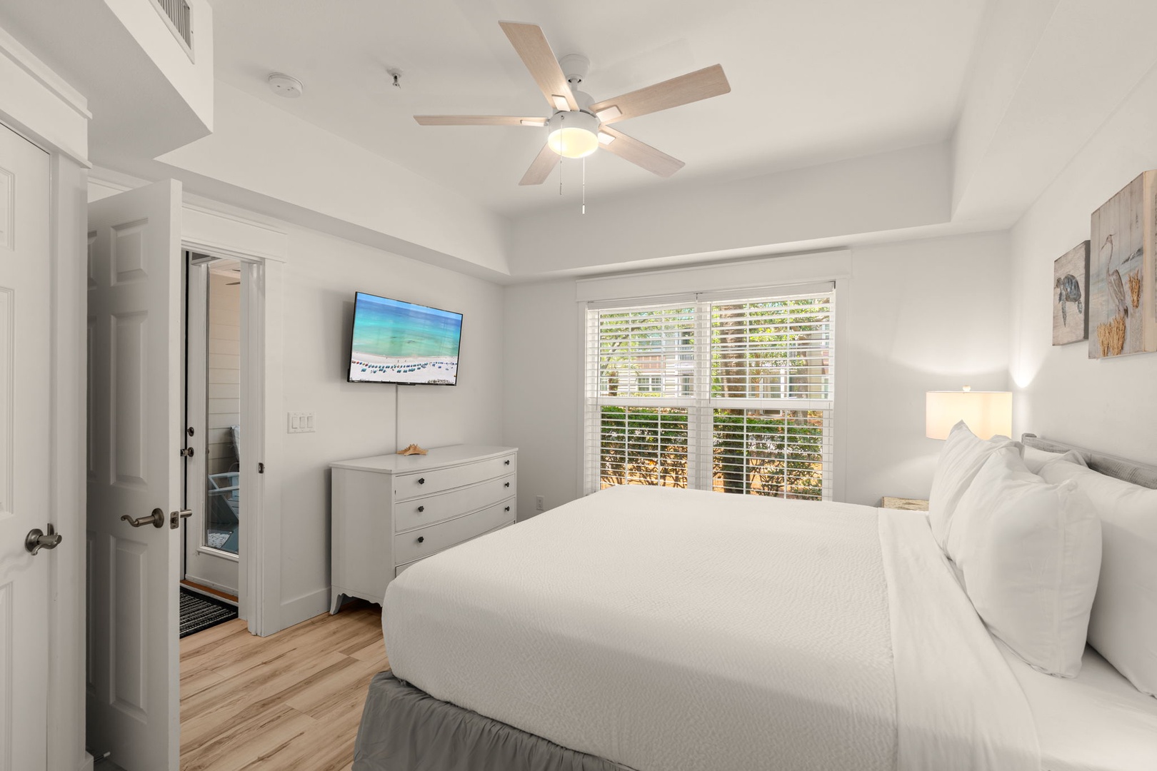 Sink into crisp linens and enjoy soft natural light filtering through plantation shutters. Your ceiling fan keeps the space perfectly cool while coastal art sets a relaxing tone for your stay.