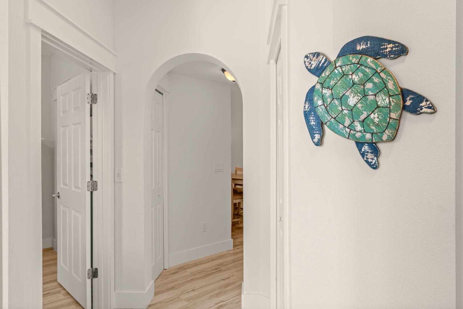 Light-filled hallway with warm wood floors and charming coastal décor, guiding you through your private retreat with beachy touches at every turn.