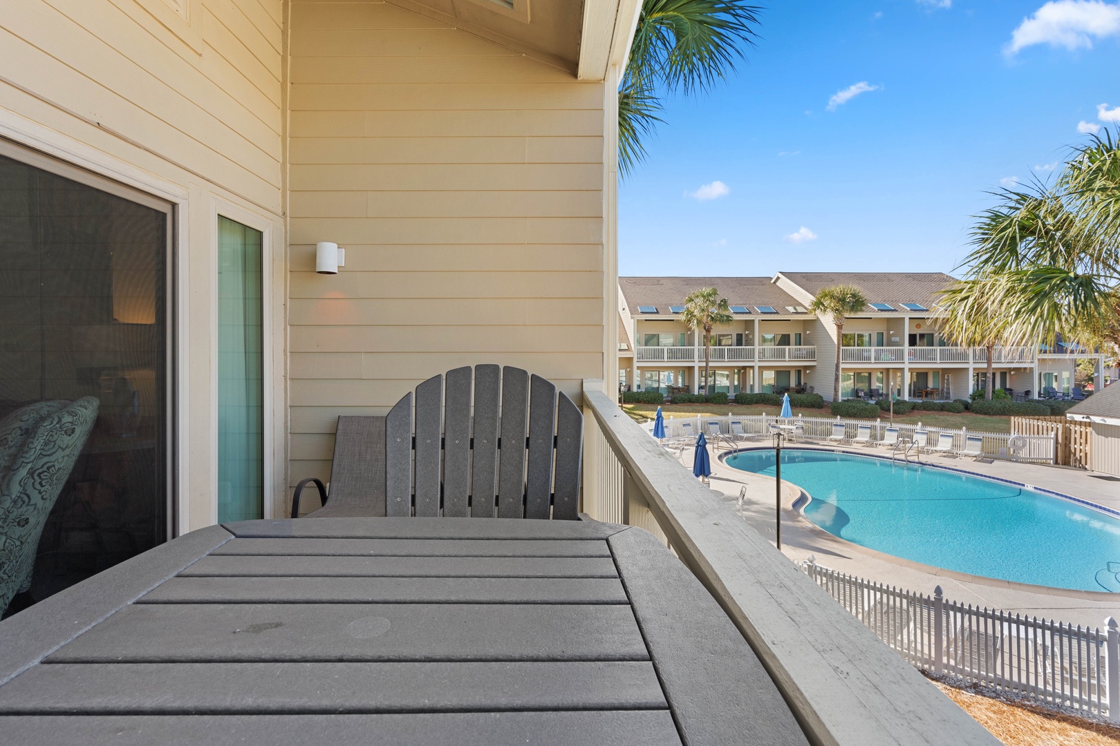 Relax on your private balcony with stunning pool views and tropical palms framing the perfect vacation backdrop.