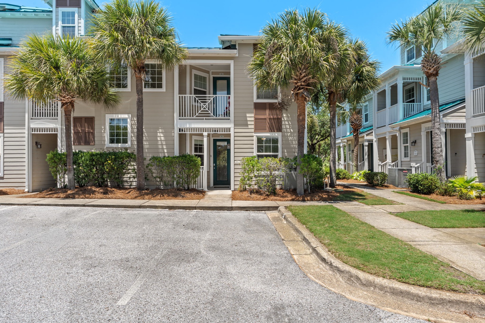 Charming coastal townhome nestled among swaying palms in a peaceful neighborhood, with a welcoming balcony and lush landscaping creating the perfect beach retreat.