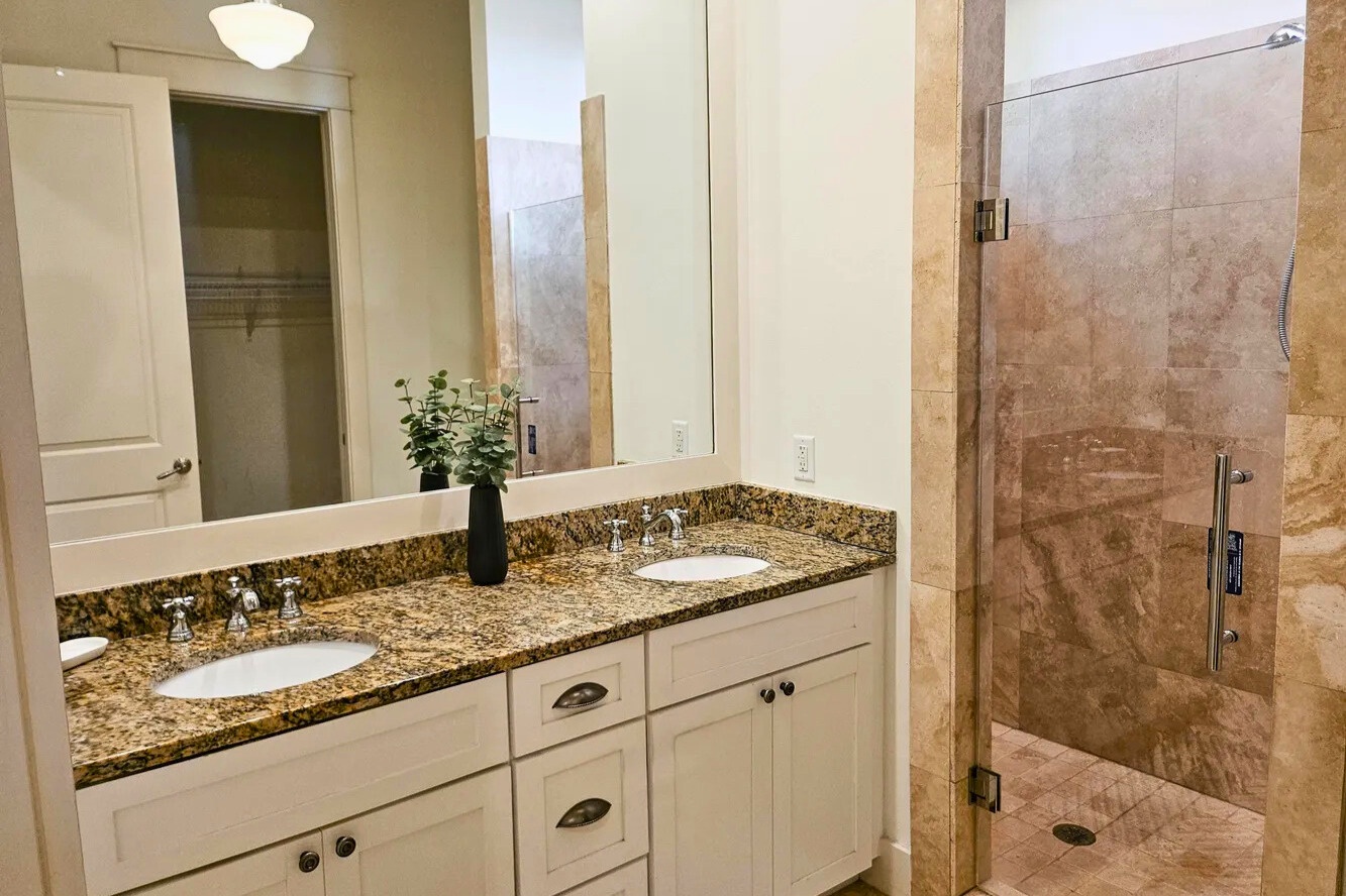 Your elegant bathroom features granite countertops, dual sinks, and a spacious glass shower with natural stone tiles for ultimate relaxation.