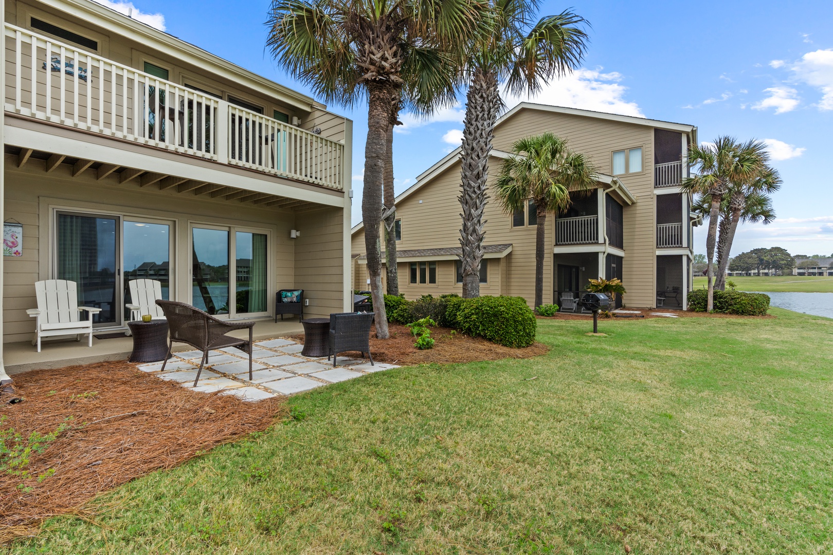 Relax on your private patio with outdoor seating while enjoying peaceful lake views through towering palm trees.