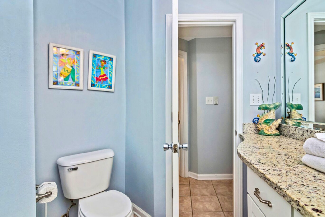 Brighten your morning routine in this cheerful bathroom featuring playful ocean-themed artwork and granite countertops with thoughtful touches throughout.