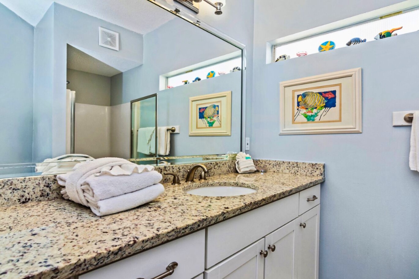 Bright coastal bathroom with granite vanity, double sinks, soft beach décor, and a clean, calming design perfect for refreshing after a day at the beach.