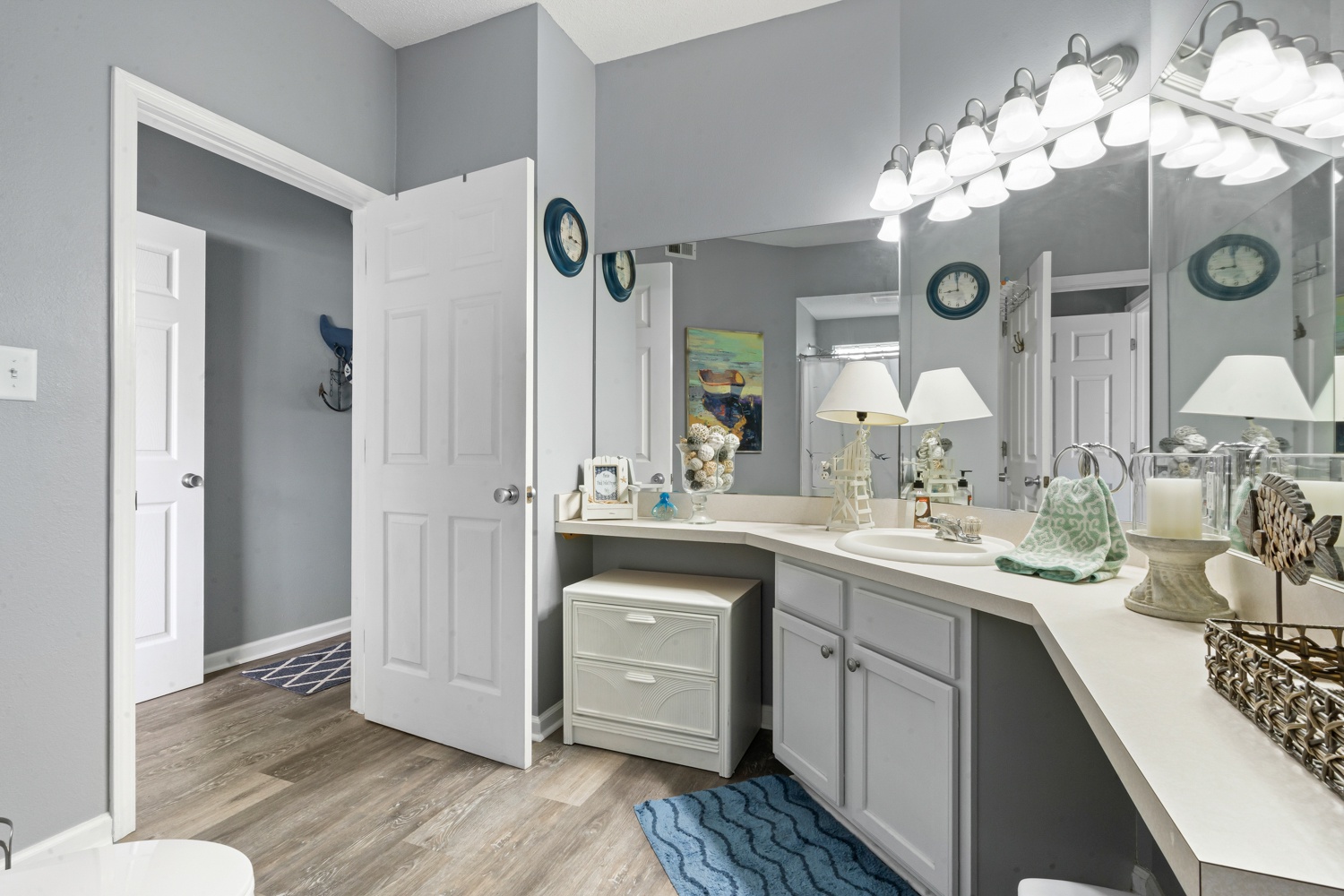 Step into your spacious bathroom featuring elegant gray cabinetry, granite countertops, and coastal-themed touches that create a serene coastal retreat atmosphere.