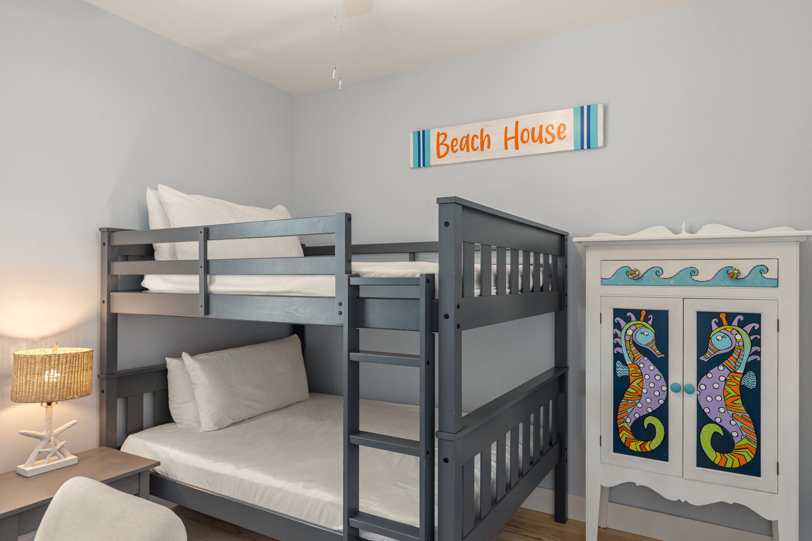 Your kids will love this beach-themed bunk room with its playful coastal décor, crisp linens, and charming seahorse details—perfect for sweet dreams near the shore.
