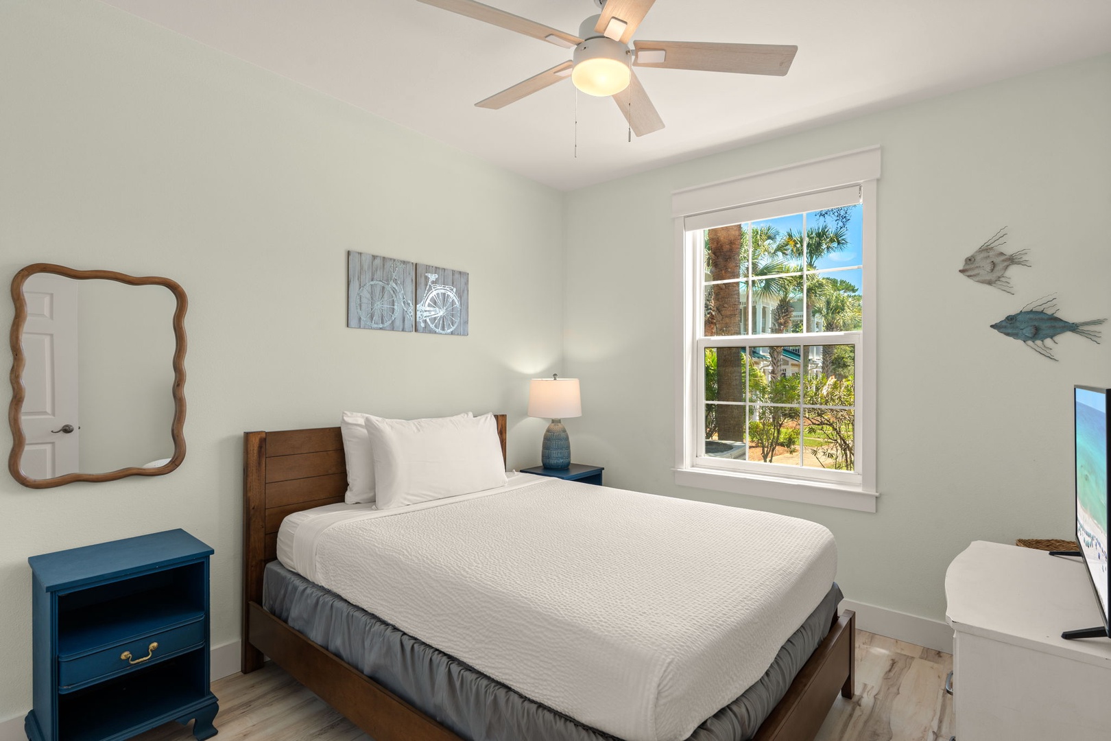 Sink into crisp linens and let the coastal breeze from your ceiling fan carry you into a restful night's sleep in this serene bedroom.