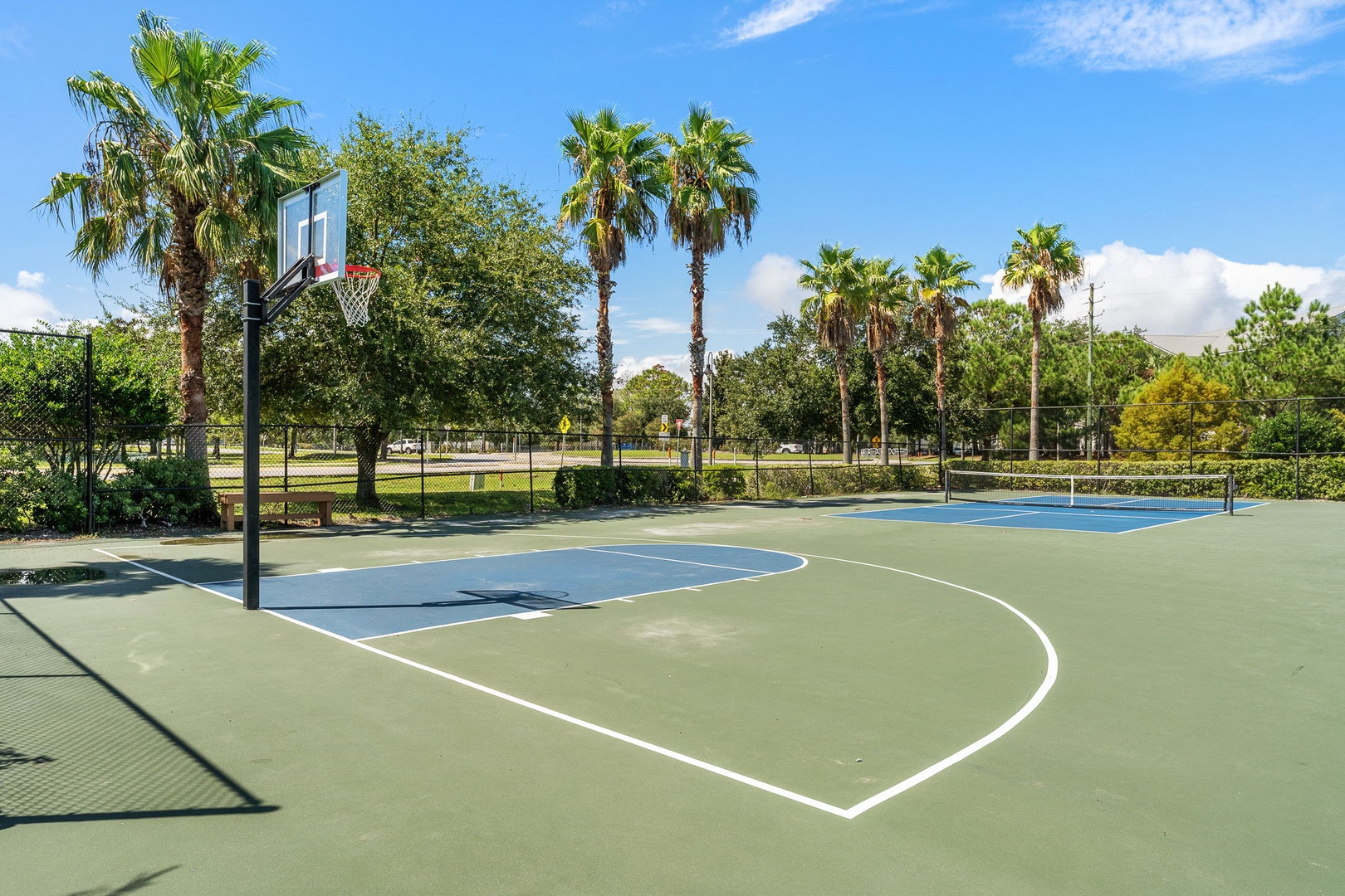 An outdoor basketball court surrounded by palm trees and lush greenery offers a scenic spot for recreation and friendly games near the property.