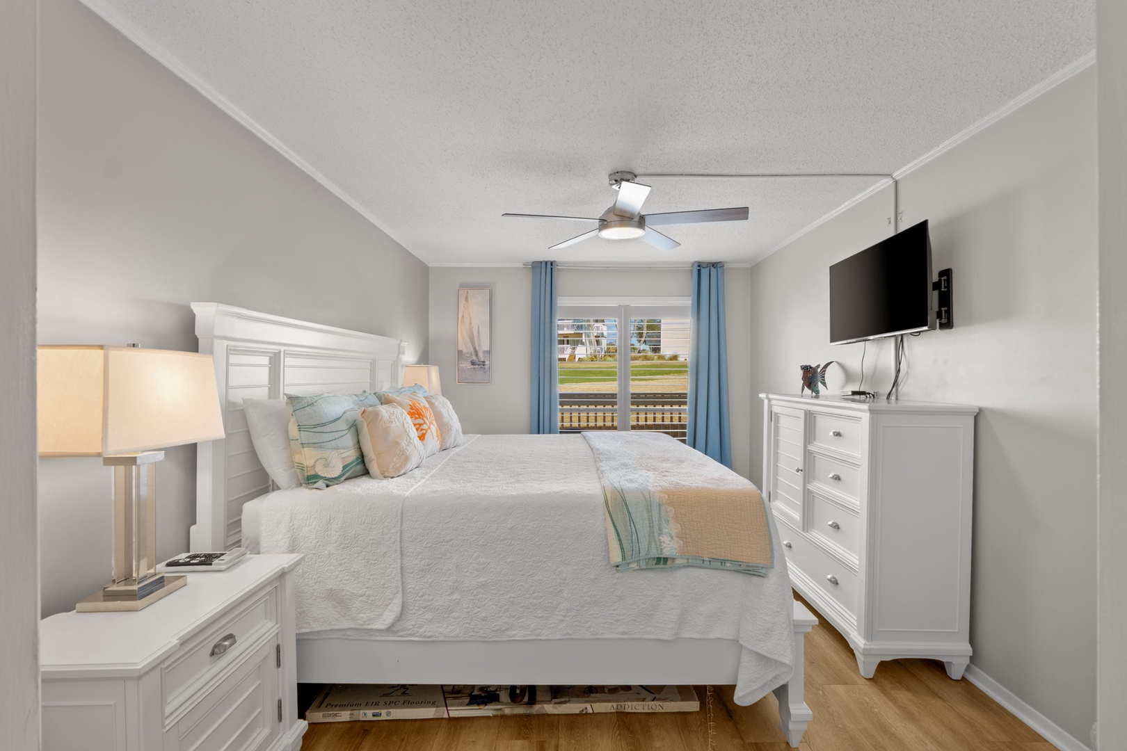 This inviting primary bedroom features a comfortable king bed, coastal-inspired furnishings, and relaxing golf course views just outside. A peaceful retreat designed for comfort, relaxation, and restful nights.