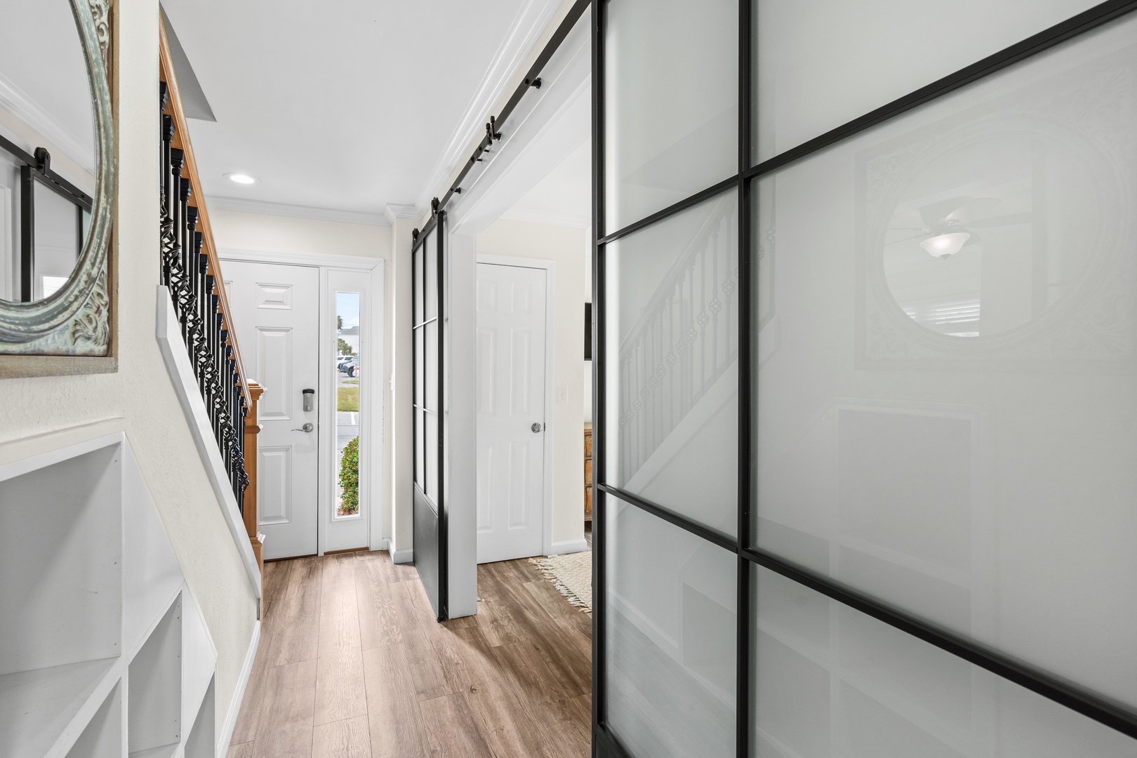 Step into your bright, modern entryway with sleek glass barn doors and warm hardwood floors welcoming you home.