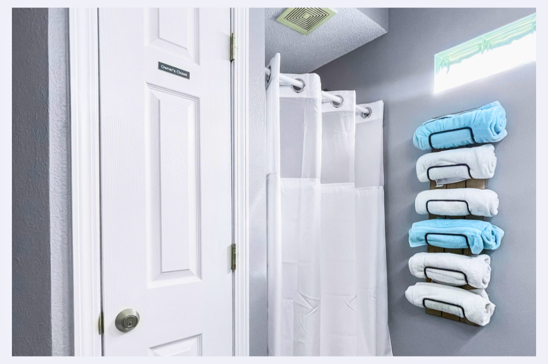 Step into your pristine bathroom where fluffy towels await on stylish wall racks, and fresh linens make every shower feel luxurious.