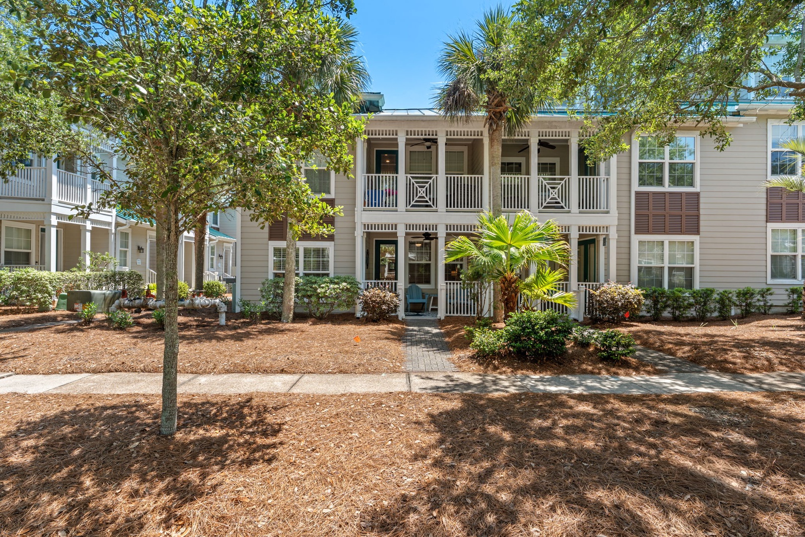 A charming coastal property showcasing classic Southern architecture with wide porches, tropical landscaping, and inviting outdoor spaces. Mature palms and lush greenery create a serene neighborhood setting.