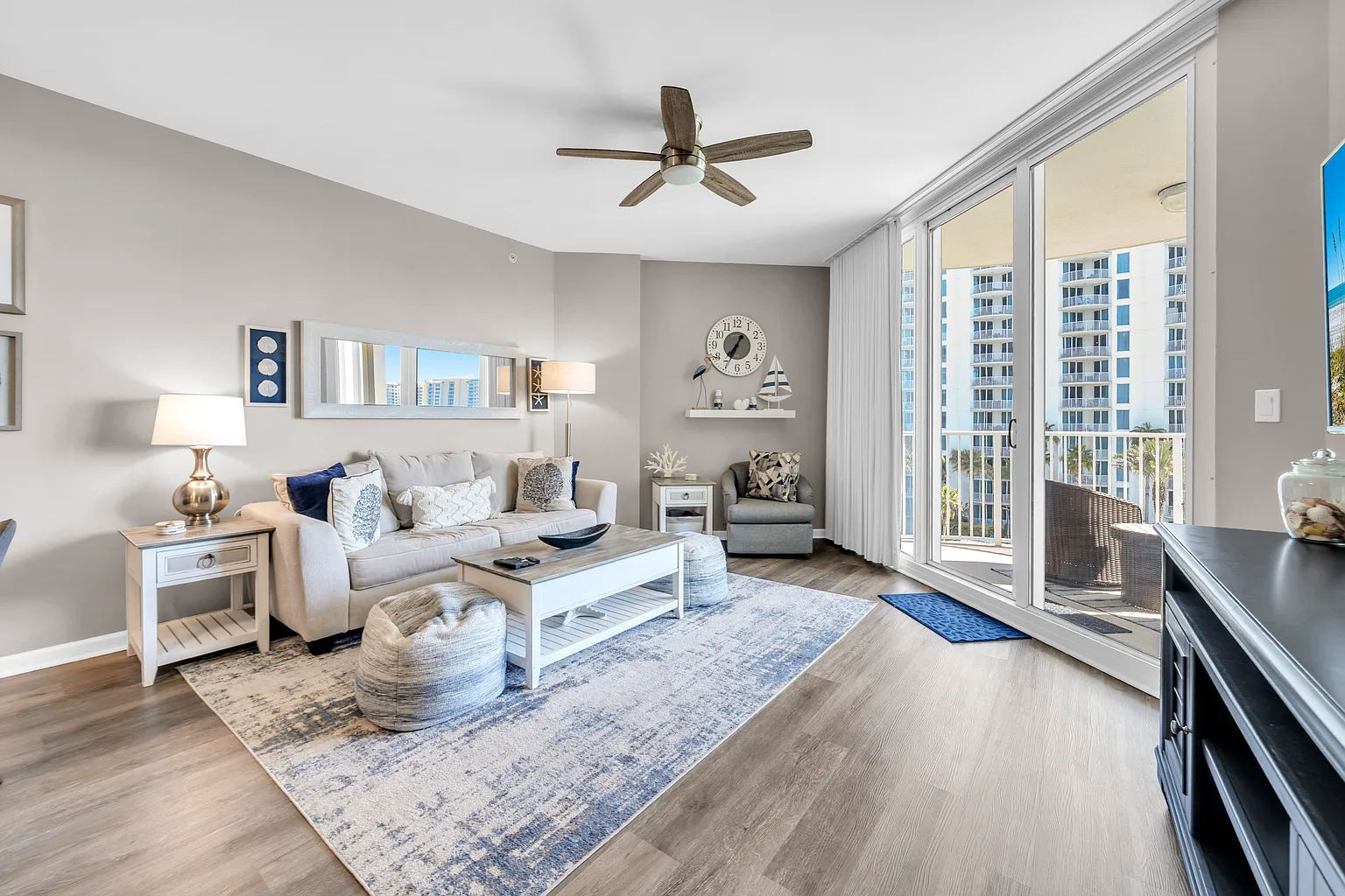 Unwind in your bright, modern living space with plush seating, coastal decor, and a private balcony overlooking city views.