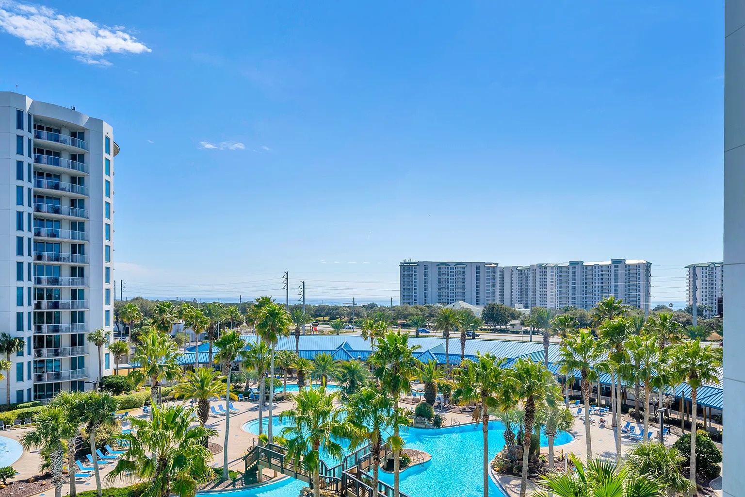 Beautiful resort view showcasing the sparkling pool area surrounded by tropical palms and modern accommodations.