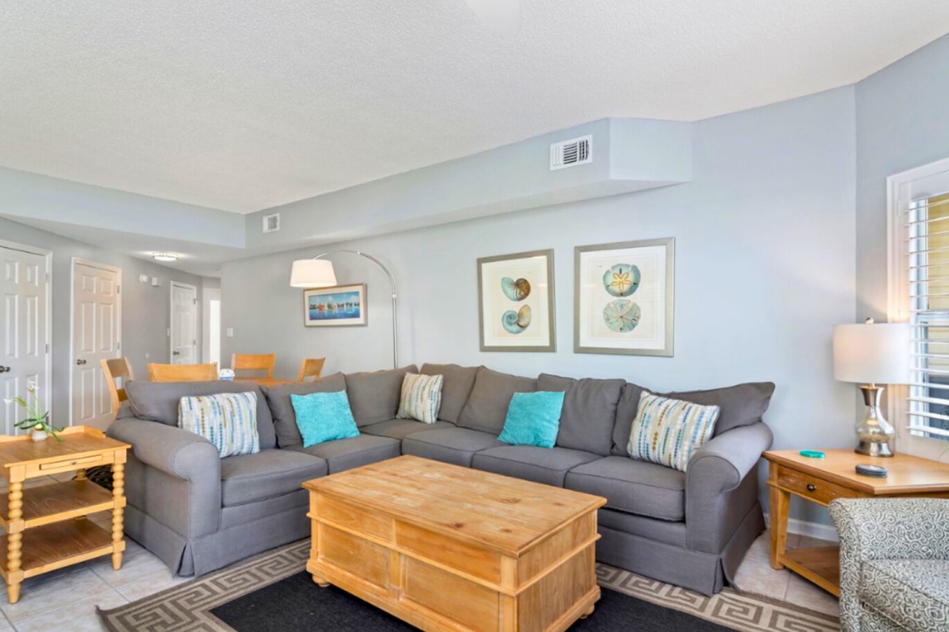 Spacious coastal living area featuring plush sectional seating, soothing beach-inspired décor, and an open layout ideal for gathering, relaxing, and enjoying time together after a day in the sun.