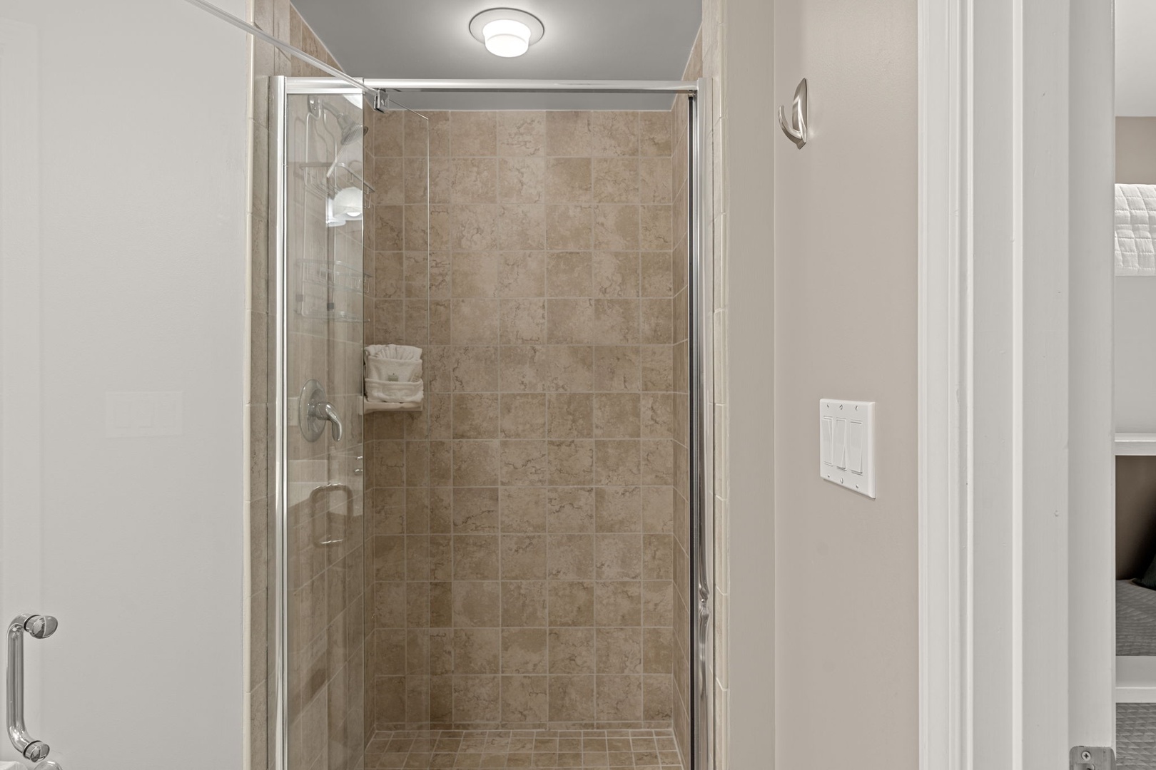 Step into a beautifully tiled walk-in shower with a spacious glass enclosure, fresh towels at hand, and warm lighting overhead for your morning refresh.