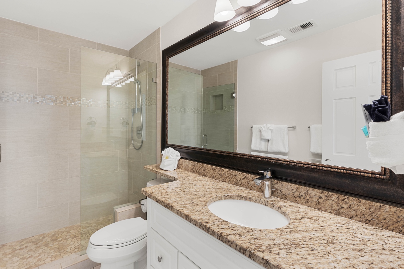 Step into your elegant bathroom featuring granite countertops, a spacious glass-enclosed shower, and thoughtfully placed amenities for your comfort.