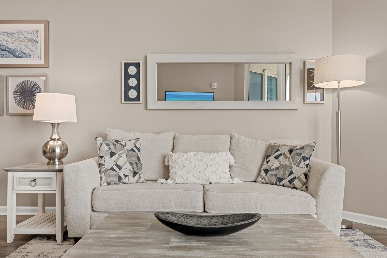 Settle into plush comfort on this elegant sofa, surrounded by soft lighting and coastal-inspired artwork that creates your perfect home away from home.