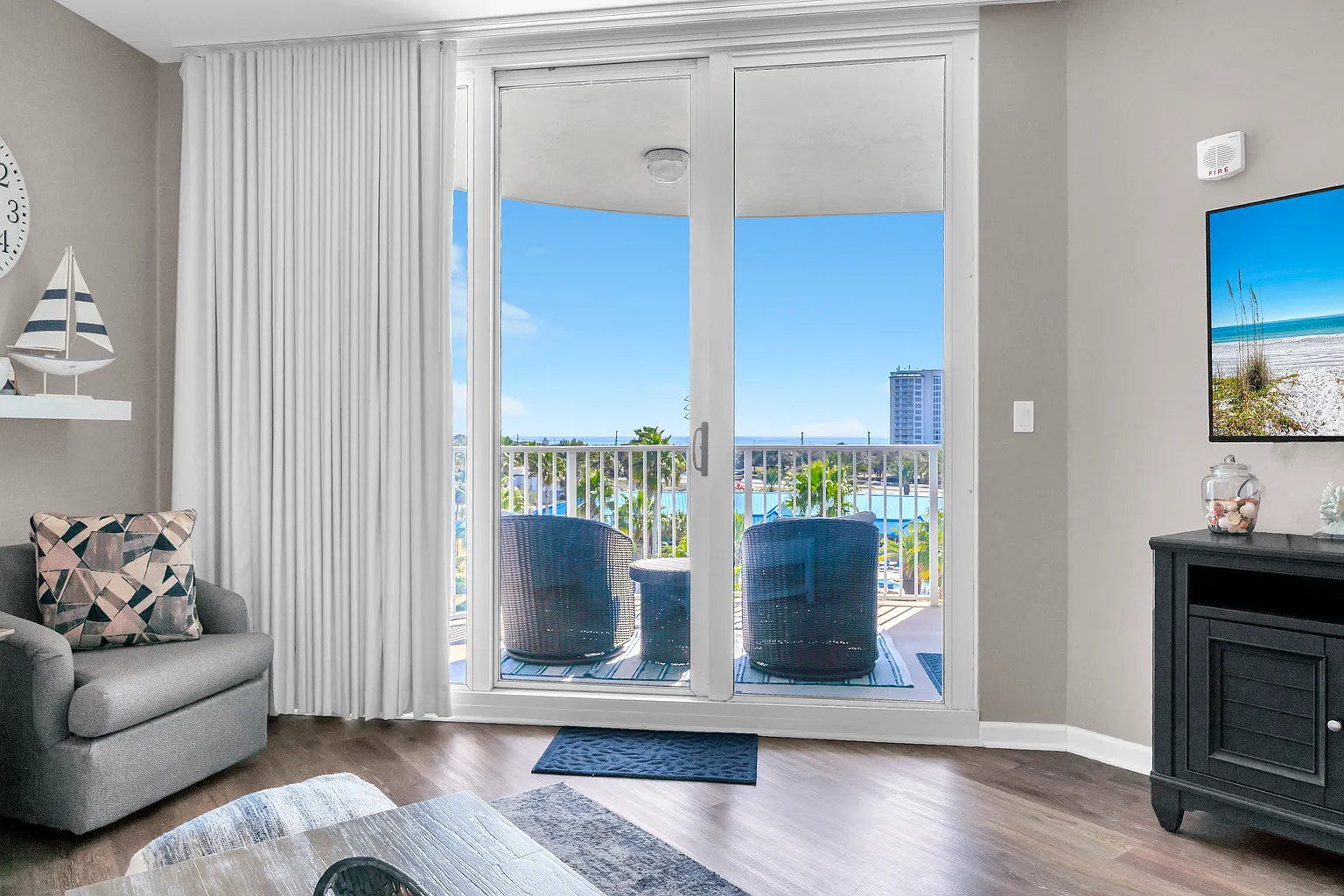 Step into your coastal retreat where floor-to-ceiling windows frame stunning ocean views. Your private balcony awaits with comfortable seating overlooking sparkling waters.